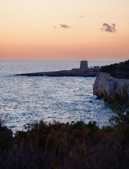 Tramonto sul mare con cielo colorato e costa all'orizzonte.